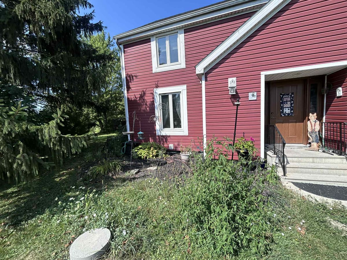 Front entry of a red house with planting beds either side of the steps